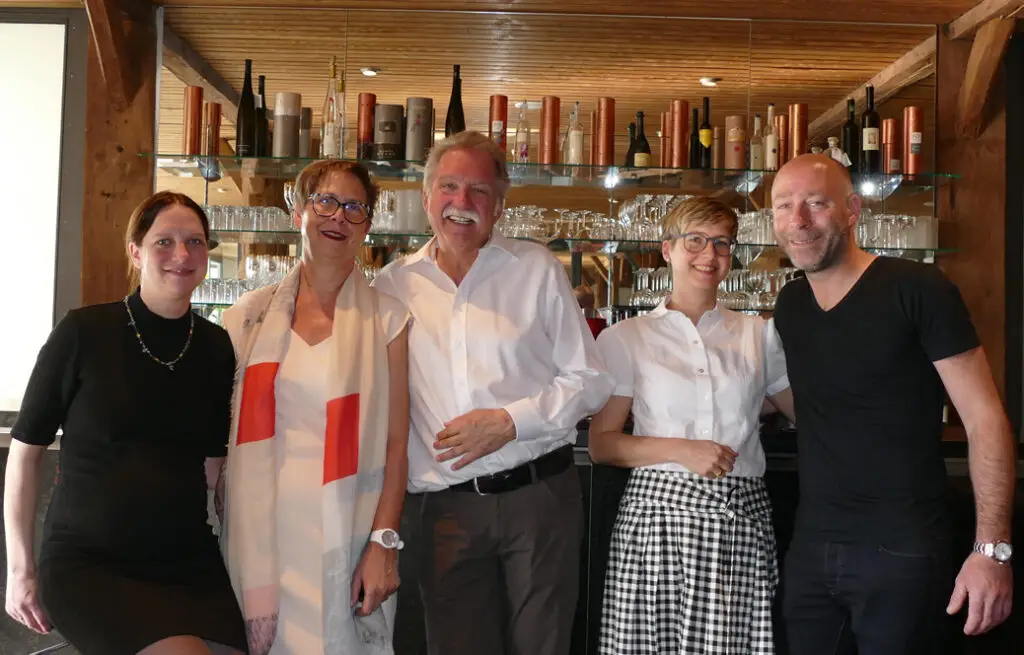 Fünf Personen der Familie Greb-Braun stehen gemeinsam im Restaurant vor einem Regal.