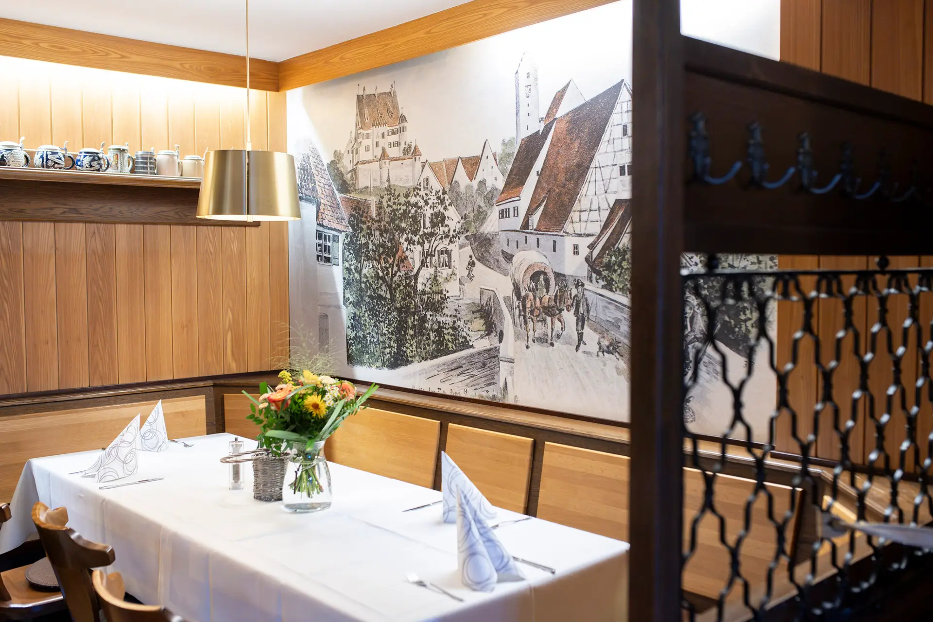 Restaurant mit Holzmöbeln, historischen Wandbildern und gedeckten Tischen.