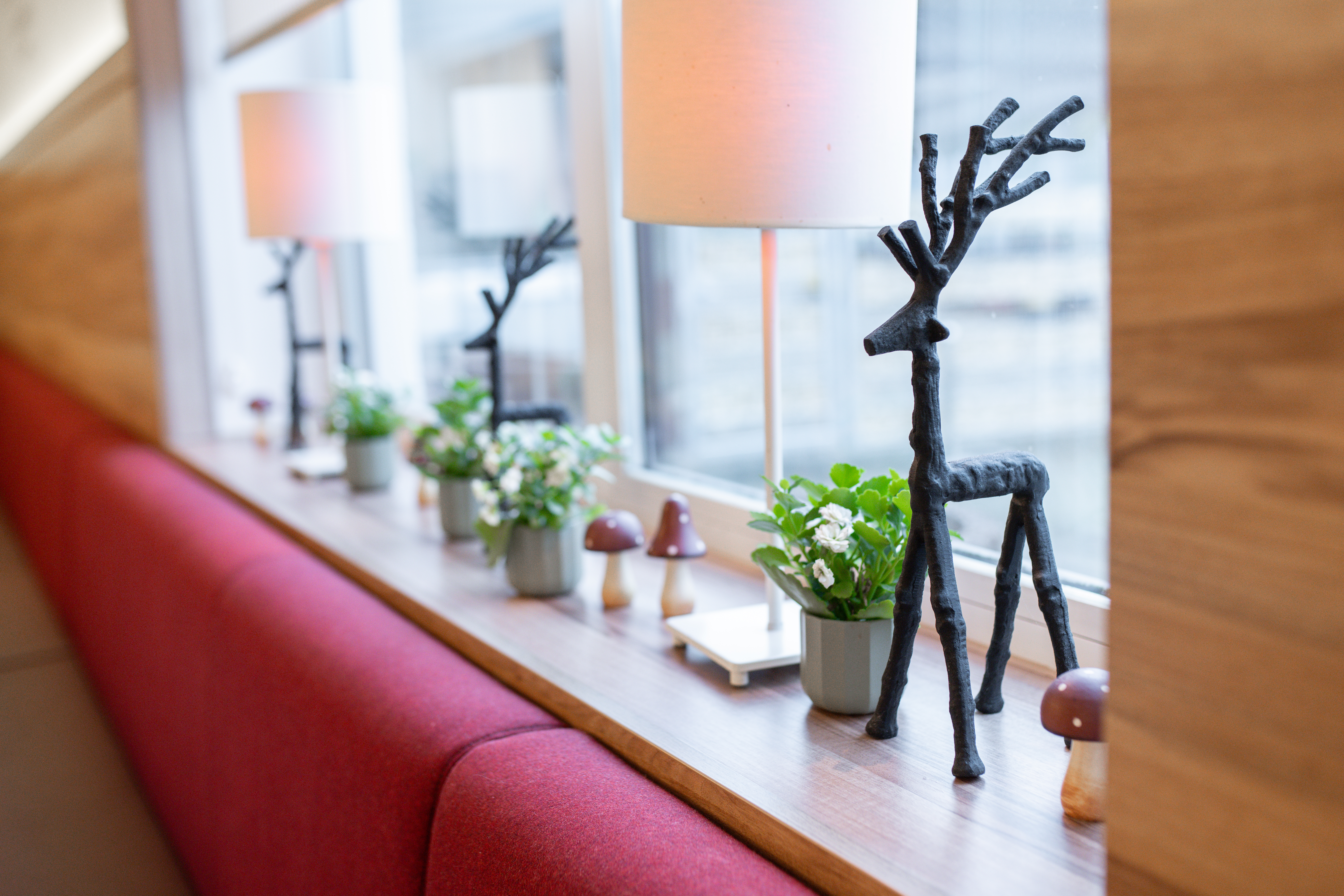 Fensterbank mit Pflanzen, Dekoration und einer Hirschfigur im Restaurant.