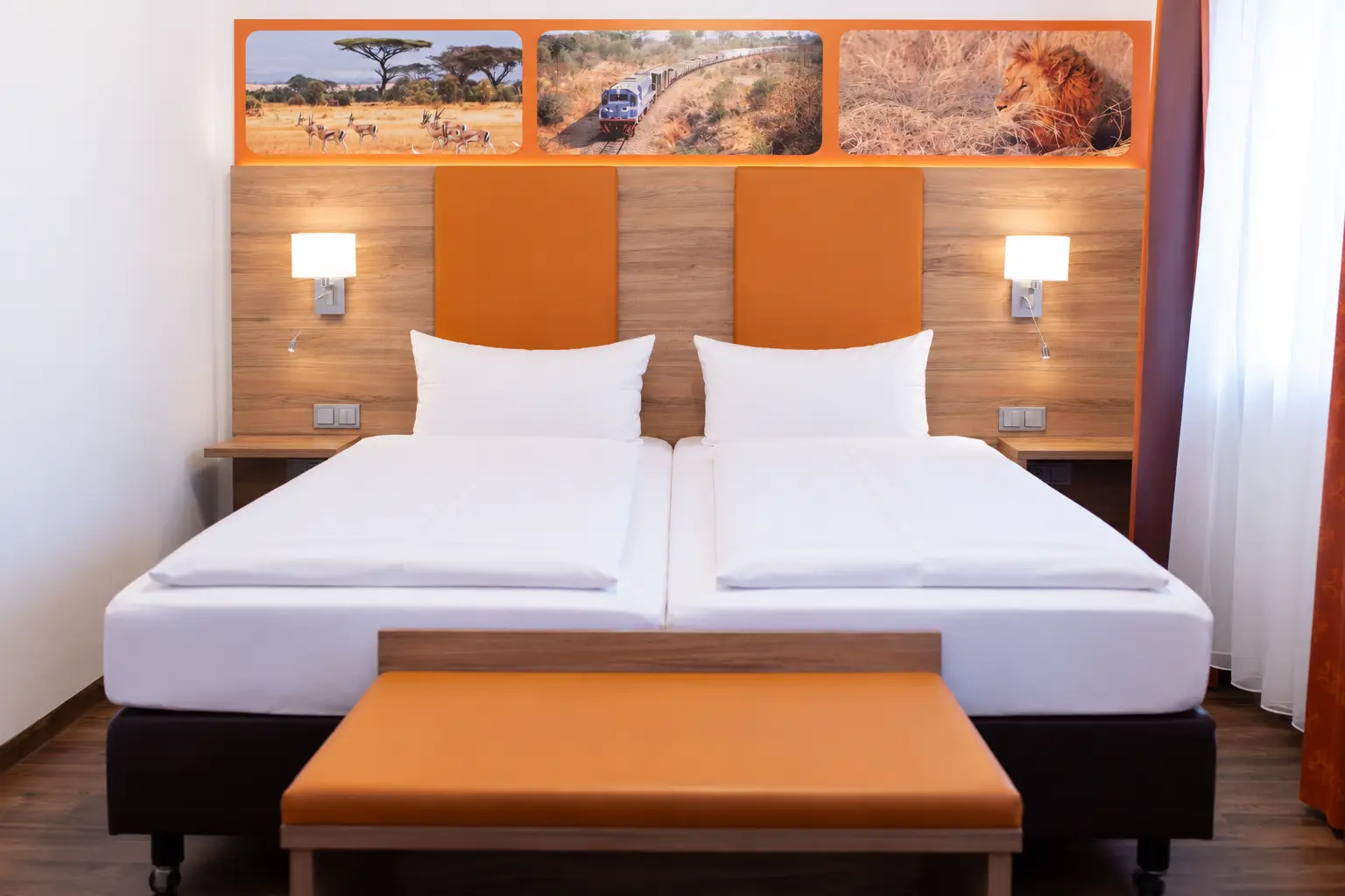 Doppelbett mit orangefarbenem Kopfteil, Holzverkleidung und zwei Wandleuchten.