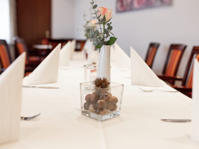 Rosafarbene Rose und natürliche Tischdekoration auf einer gedeckten Tafel.