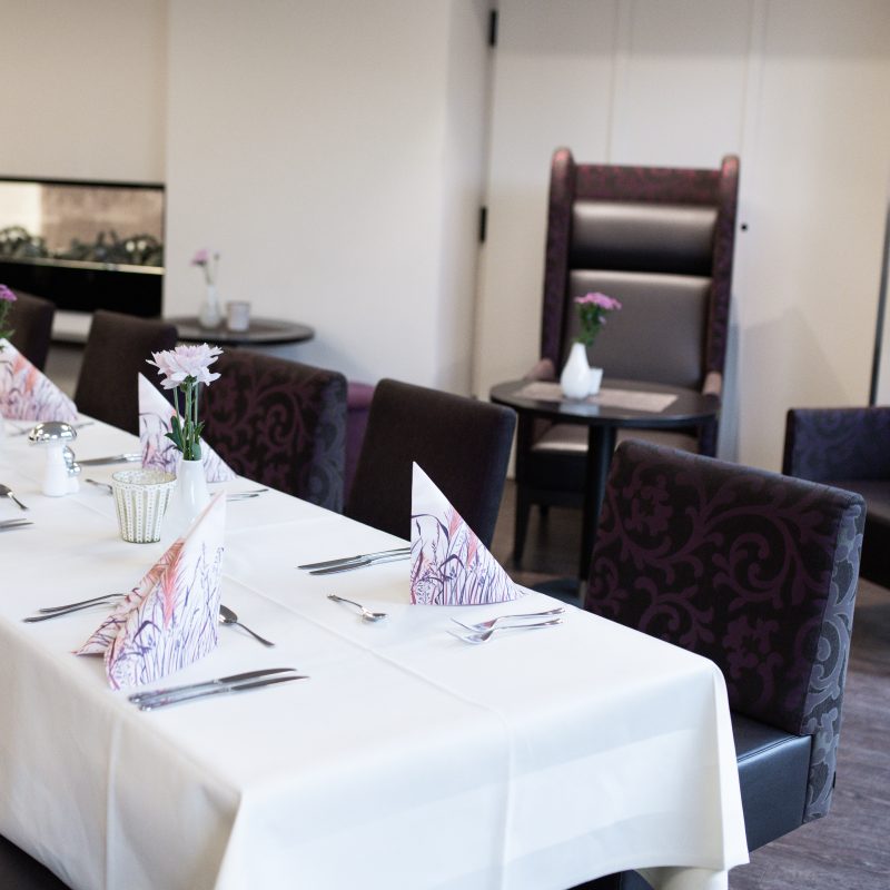 Gemütlicher Restaurantbereich mit gedeckten Tischen und gepolsterten Stühlen.