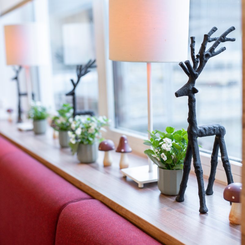 Fensterbank mit Pflanzen, Dekoration und einer Hirschfigur im Restaurant.