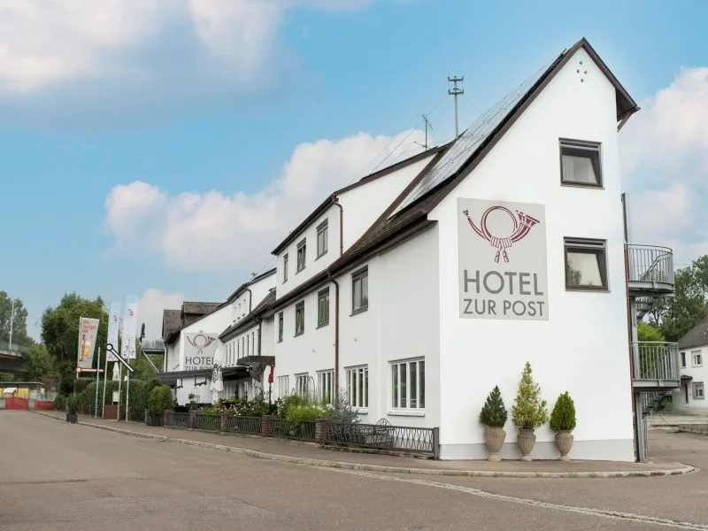 Außenansicht des Hotel Gasthof Post in Leipheim bei Günzburg mit weißer Fassade, Satteldach und Hotelschriftzug.