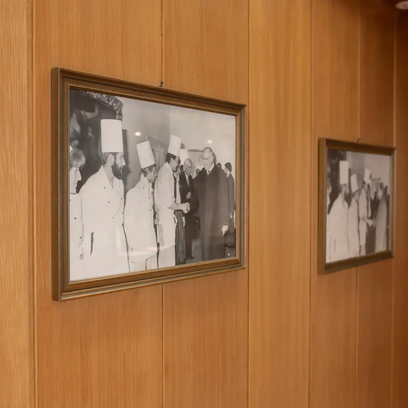 Gerahmte historische Schwarz-Weiß-Fotografien an einer holzverkleideten Wand.