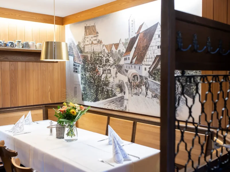 Restaurant mit Holzmöbeln, historischen Wandbildern und gedeckten Tischen.