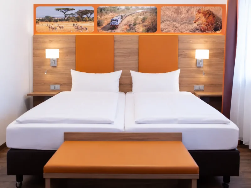 Doppelbett mit orangefarbenem Kopfteil, Holzverkleidung und zwei Wandleuchten.