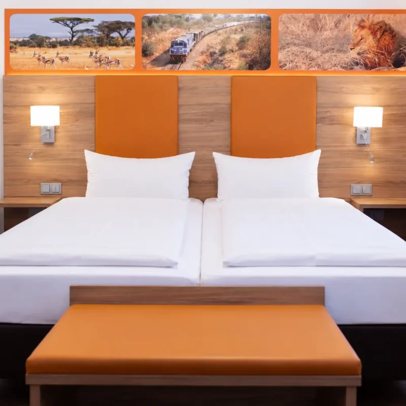 Doppelbett mit orangefarbenem Kopfteil, Holzverkleidung und zwei Wandleuchten.