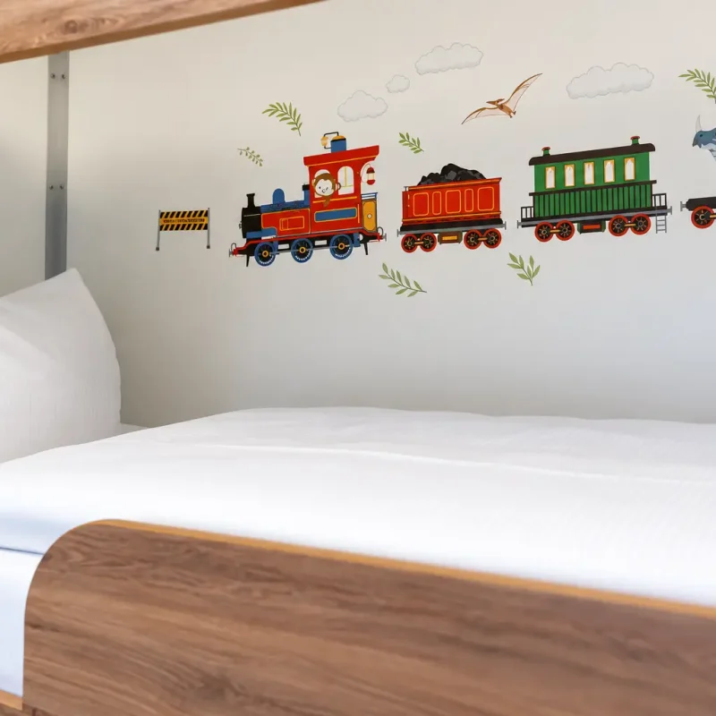 Helles Bett mit bunter Eisenbahn als Wanddekoration.