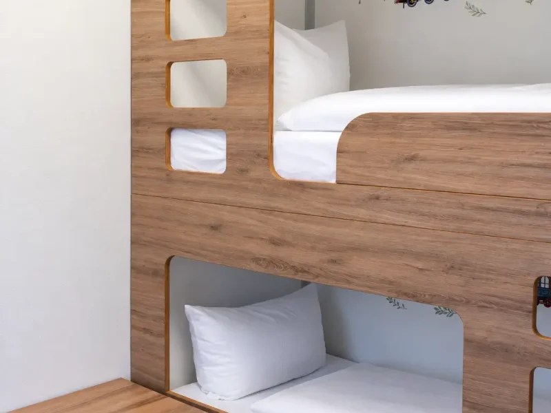 Etagenbett aus Holz mit wei&szlig;en Kissen und Bettdecken.