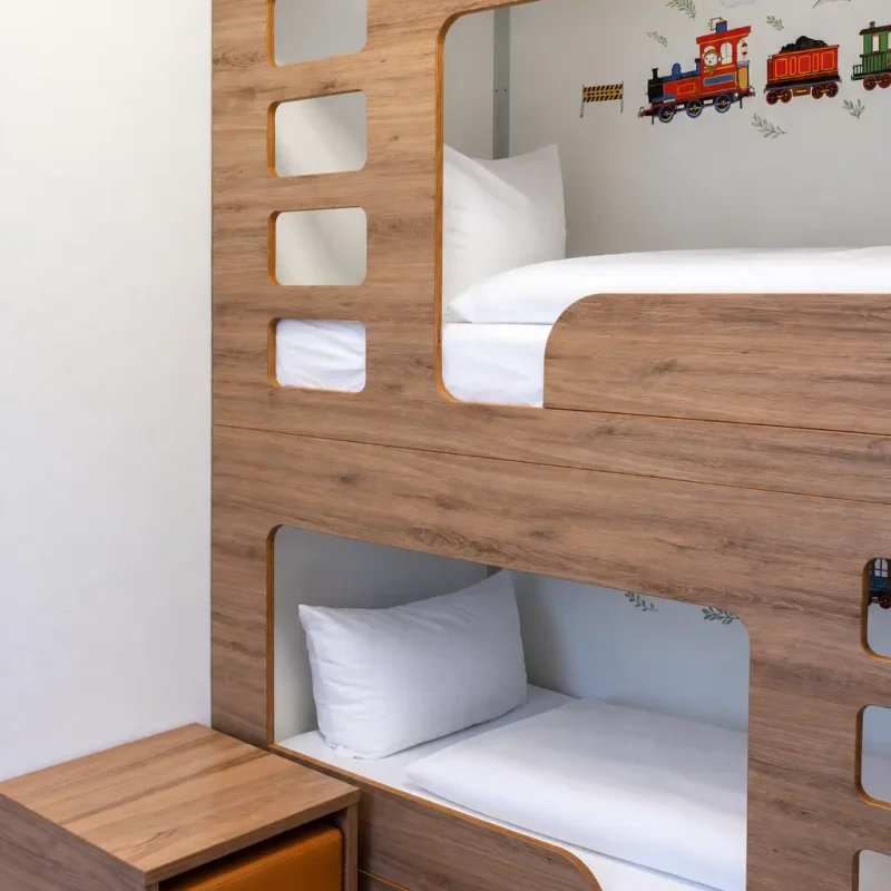 Etagenbett aus Holz mit wei&szlig;en Kissen und Bettdecken.