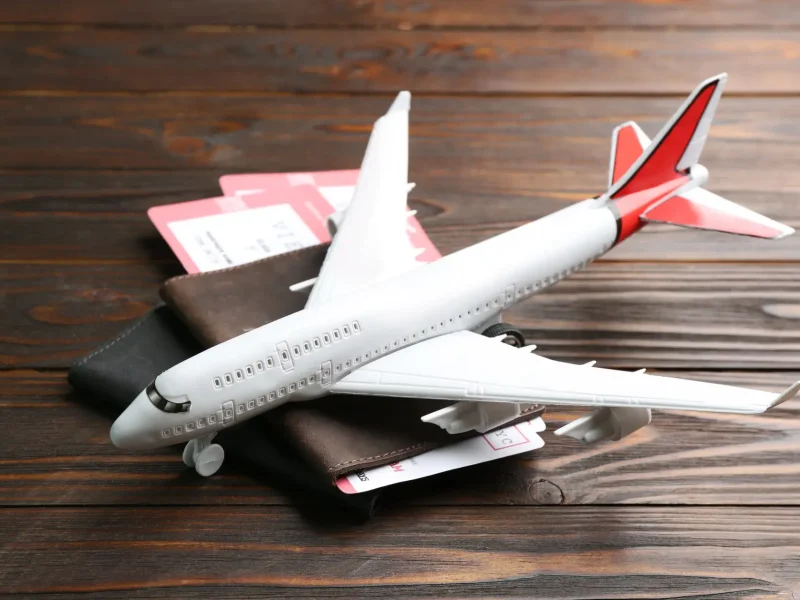 Wei&szlig;es Modellpassagierflugzeug mit roten Leitwerksdetails auf einer Holzoberfl&auml;che.