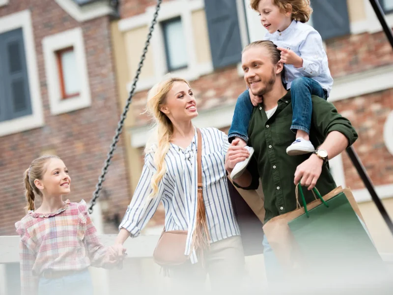 Familie mit Kindern freut sich gemeinsam auf einer Schaukel im Freien.
